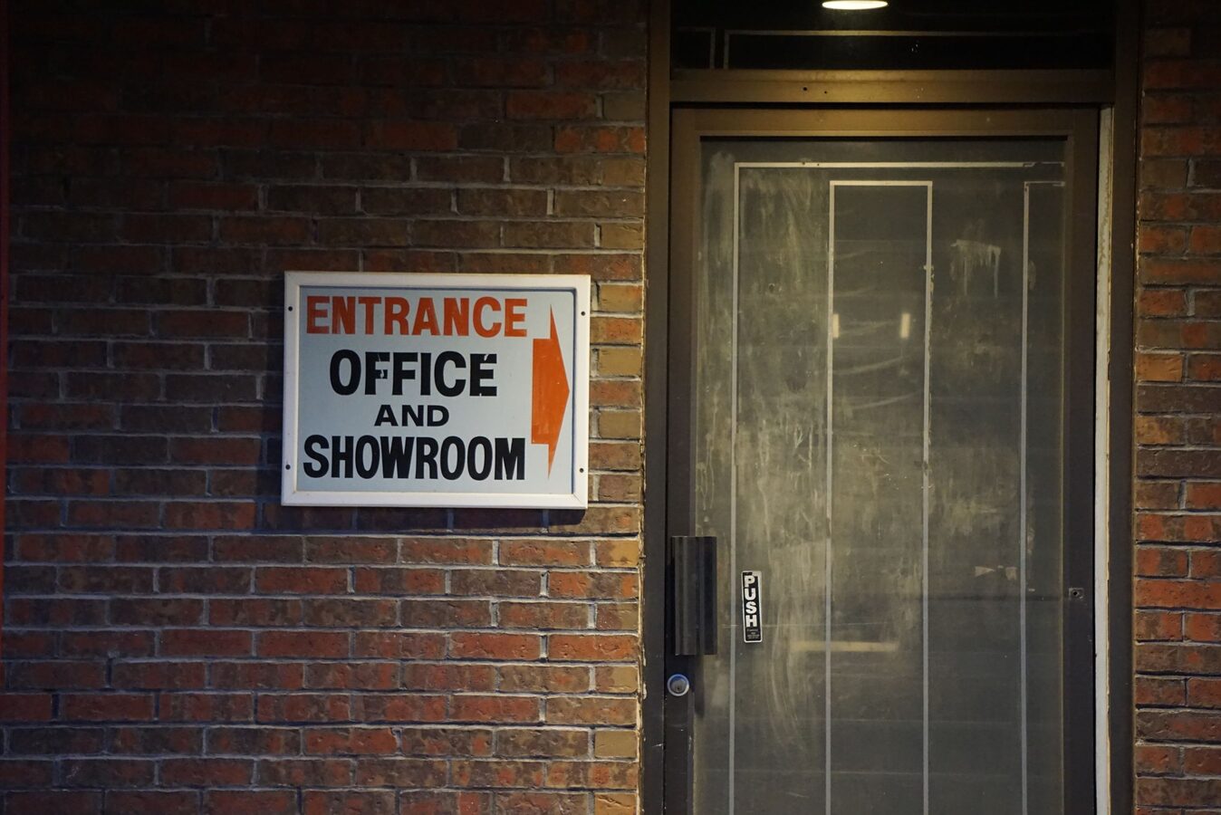 Commercial office entrance door with a push plate on a brick storefront