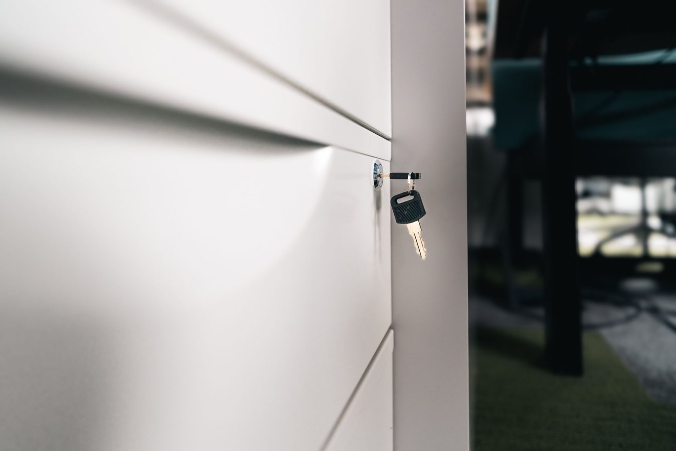 Key left in the lock of a white office file cabinet drawer