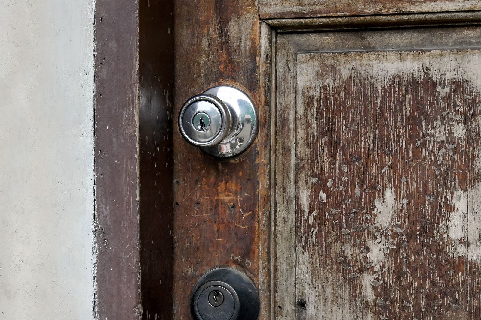 Weathered apartment door with a keyed knob and a second lock cylinder below it