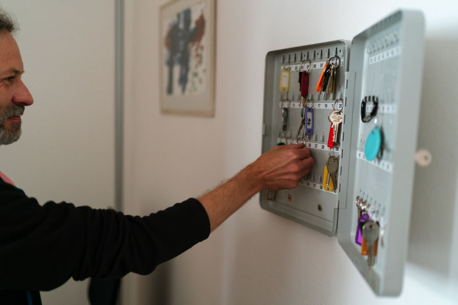 Person taking a numbered spare key from a wall-mounted key cabinet