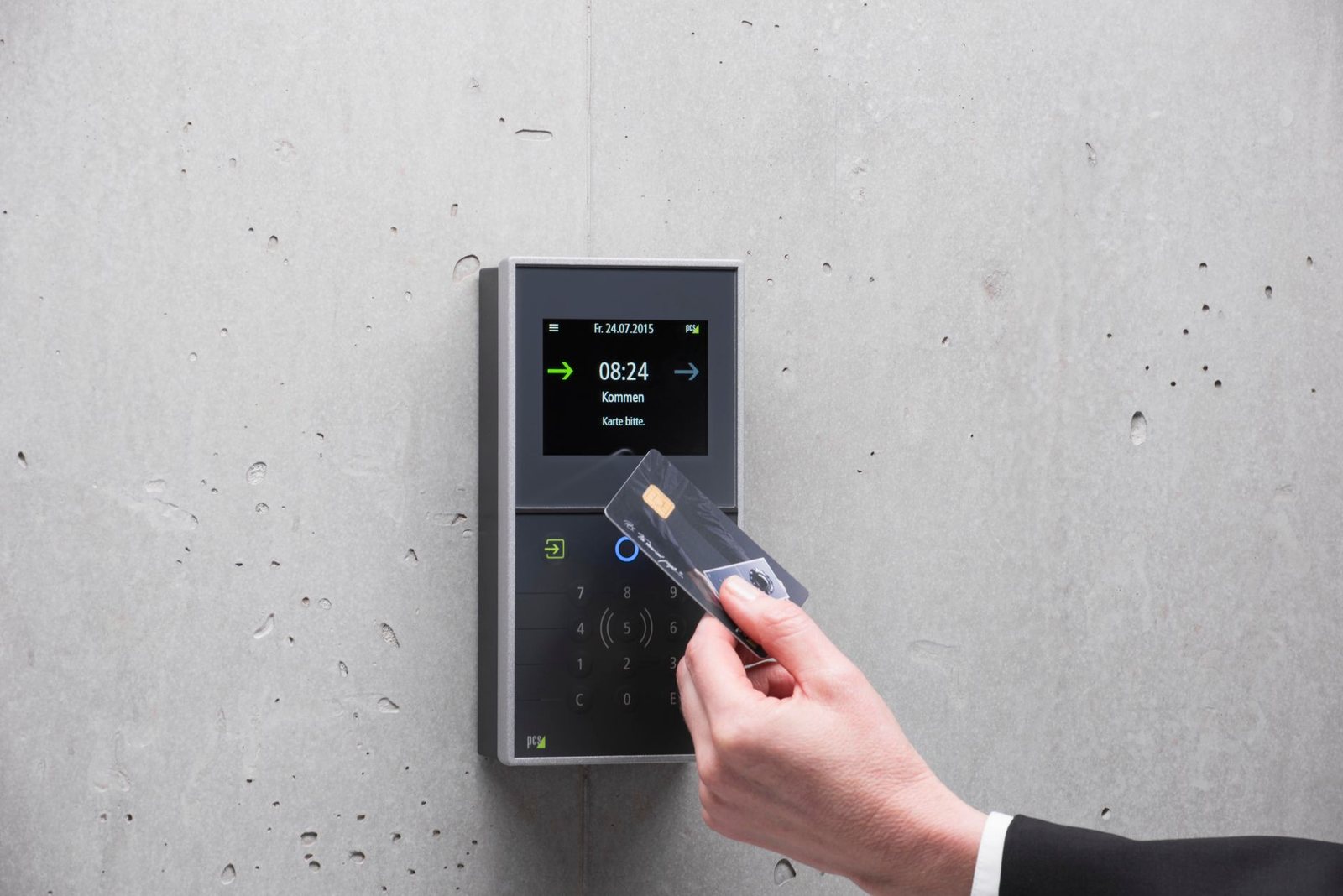 Hand presenting an access credential to a wall-mounted card and fob reader at a building entrance