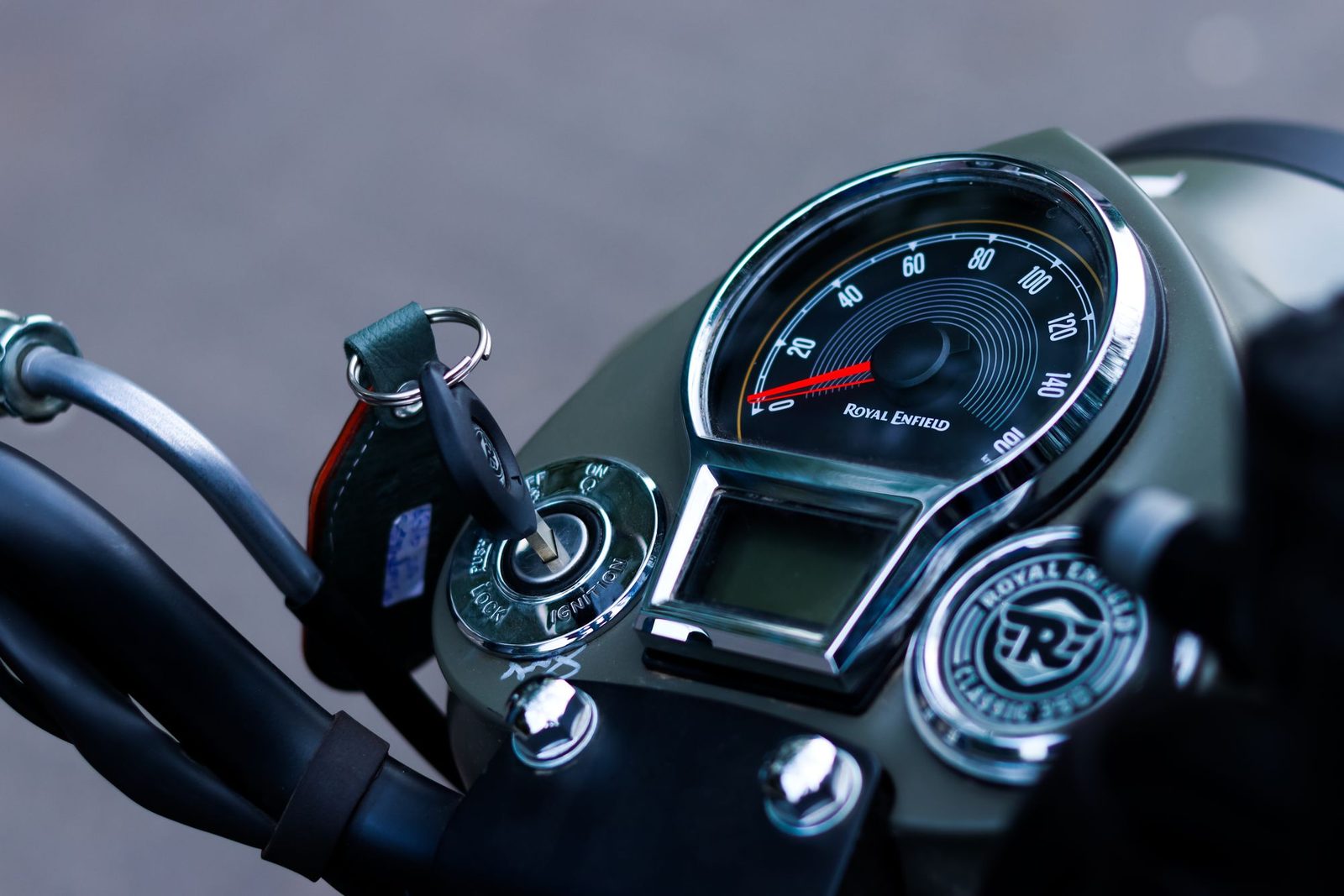 Close-up of a motorcycle ignition barrel with the key inserted beside the speedometer
