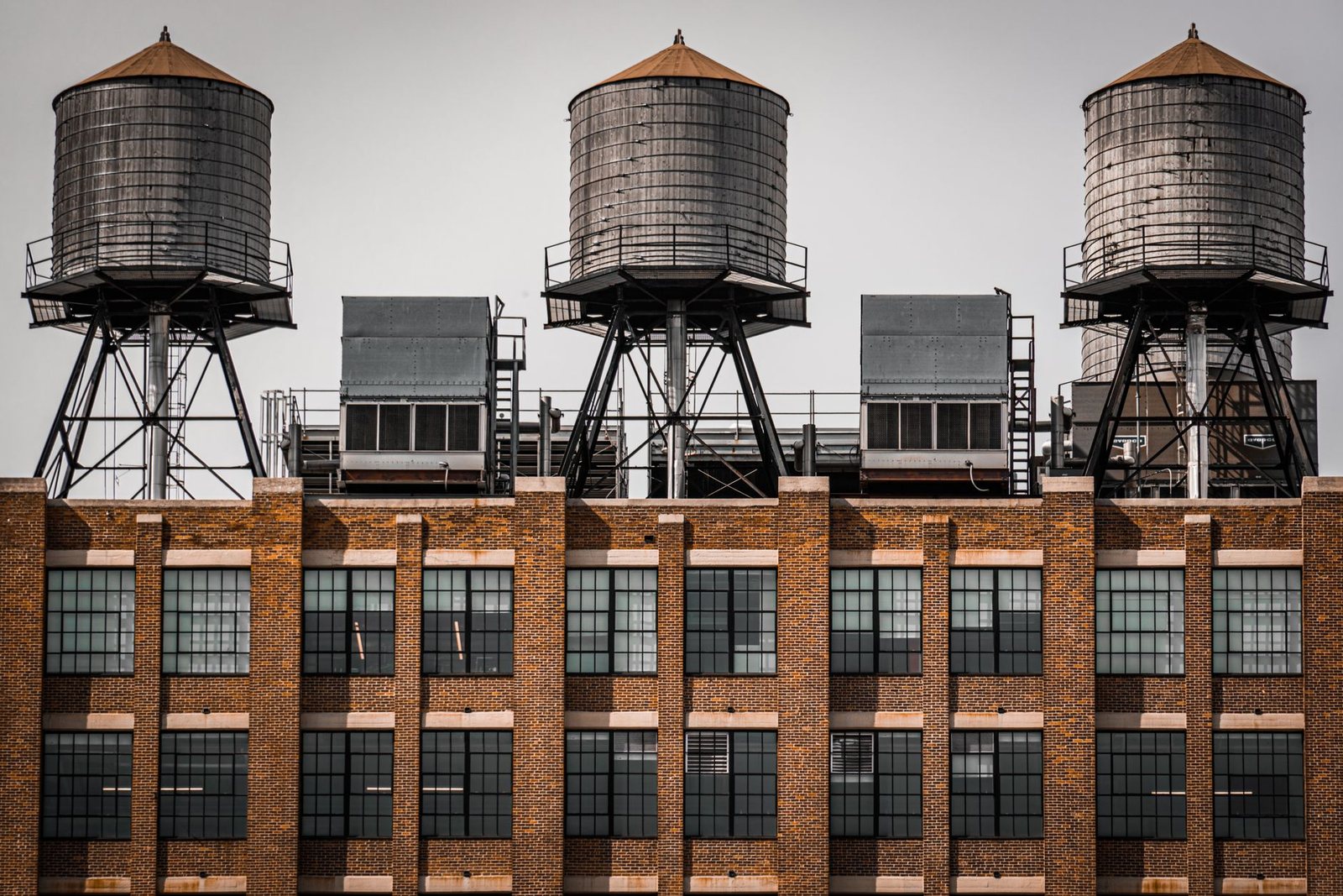 Wooden water towers and rooftop mechanical equipment above the brick facade of a New York City building