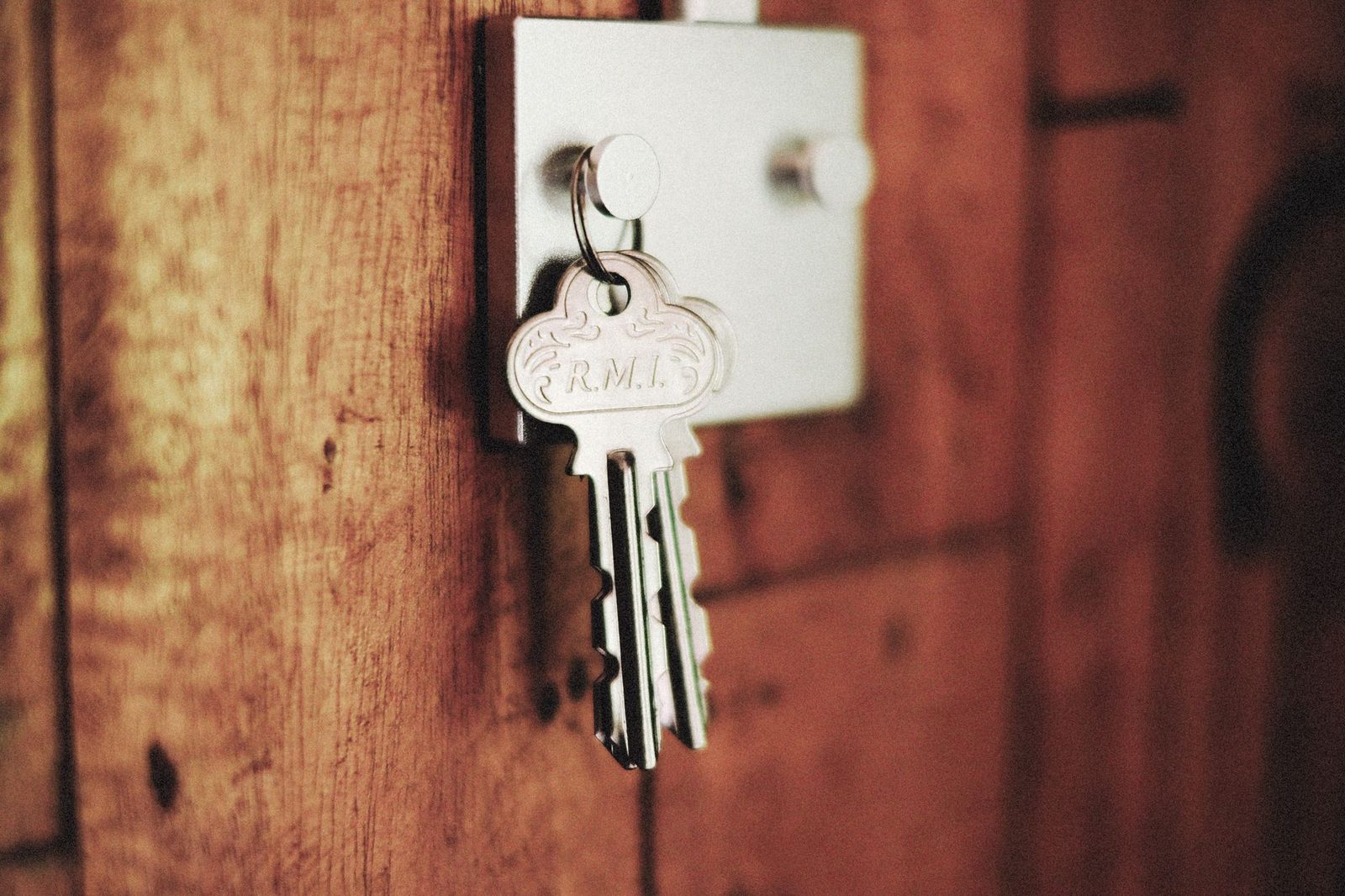 Pair of apartment keys on a ring left hanging in the lock of a wooden door