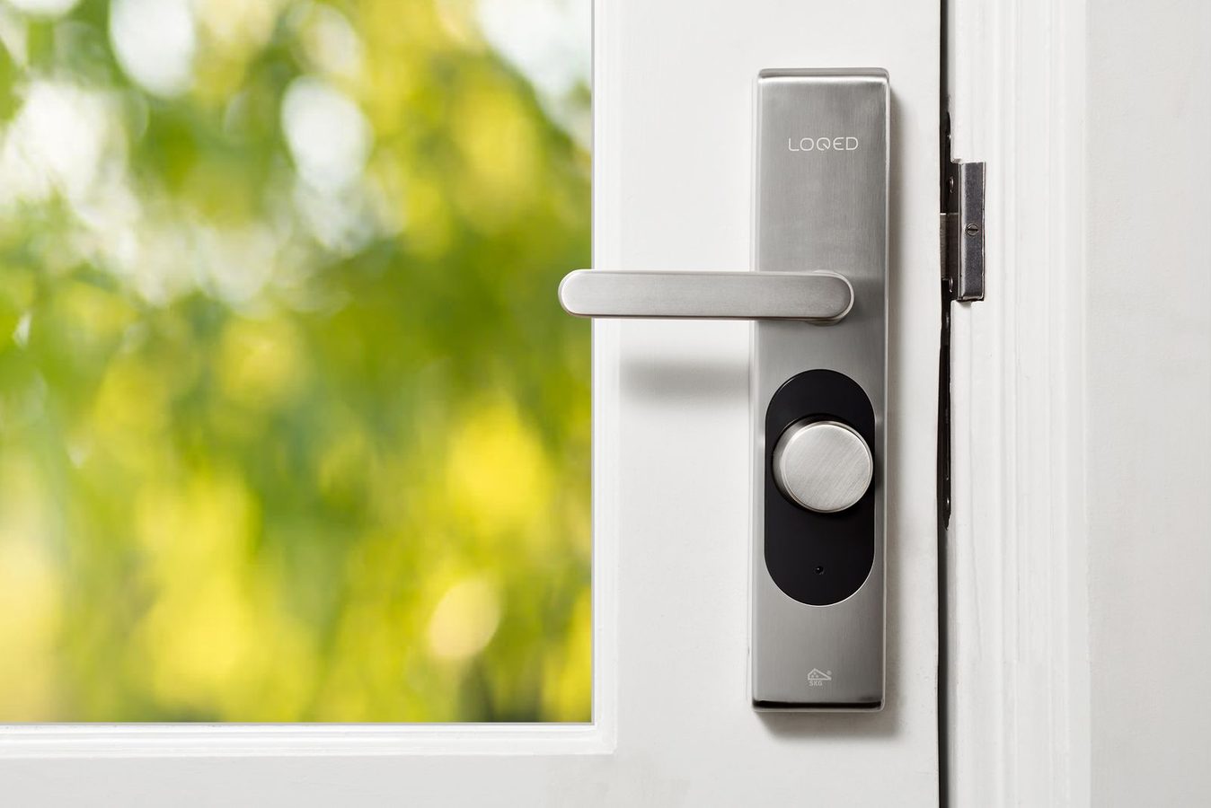 Electronic smart lock with a handle and thumbturn mounted on a white entrance door