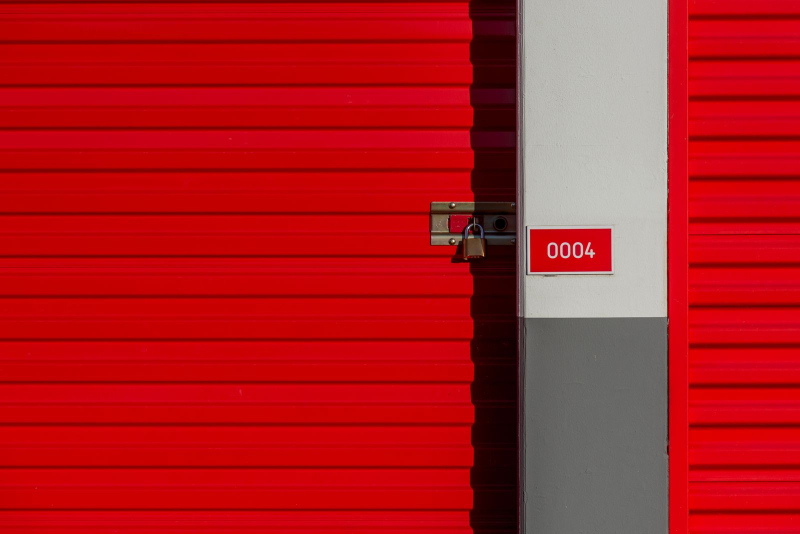 Red storage unit door with padlock at a self-storage facility