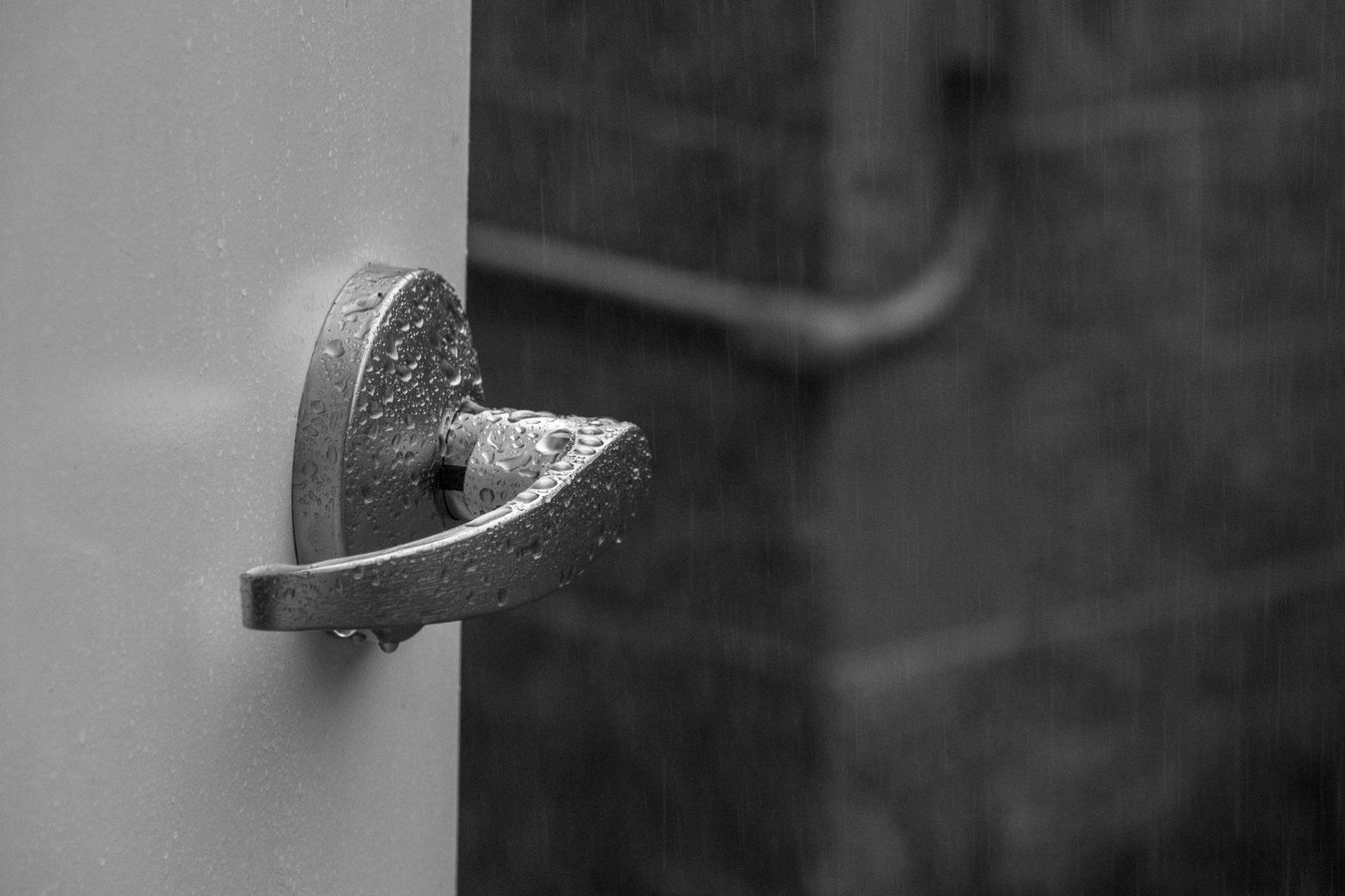 Rain-soaked exterior door handle and lock during a storm