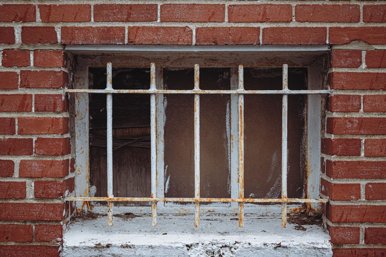 Barred ground-floor window set into a red brick wall on a city building