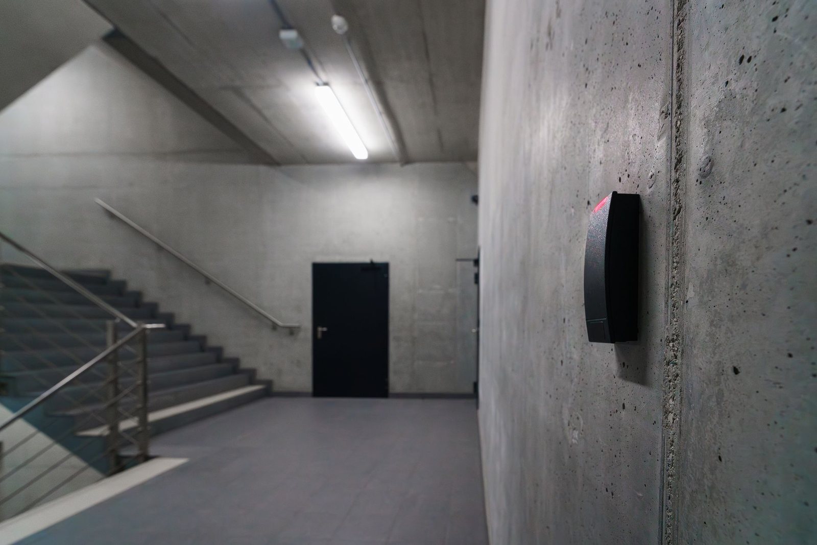 Card and fob reader mounted on a wall beside a secured stairwell door inside a building