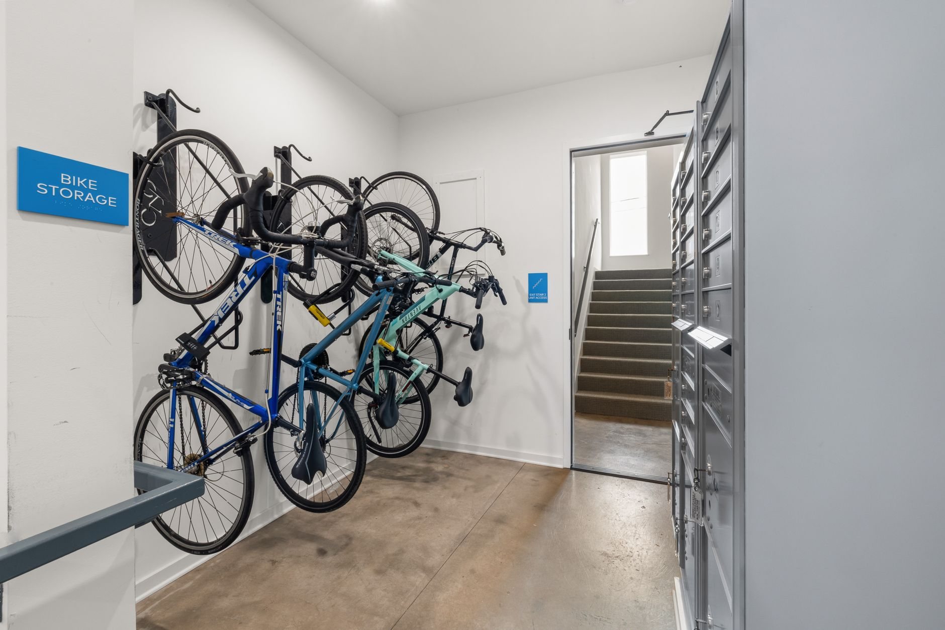 Building bike storage room with bicycles on wall racks beside a mail locker wall and a stair access door