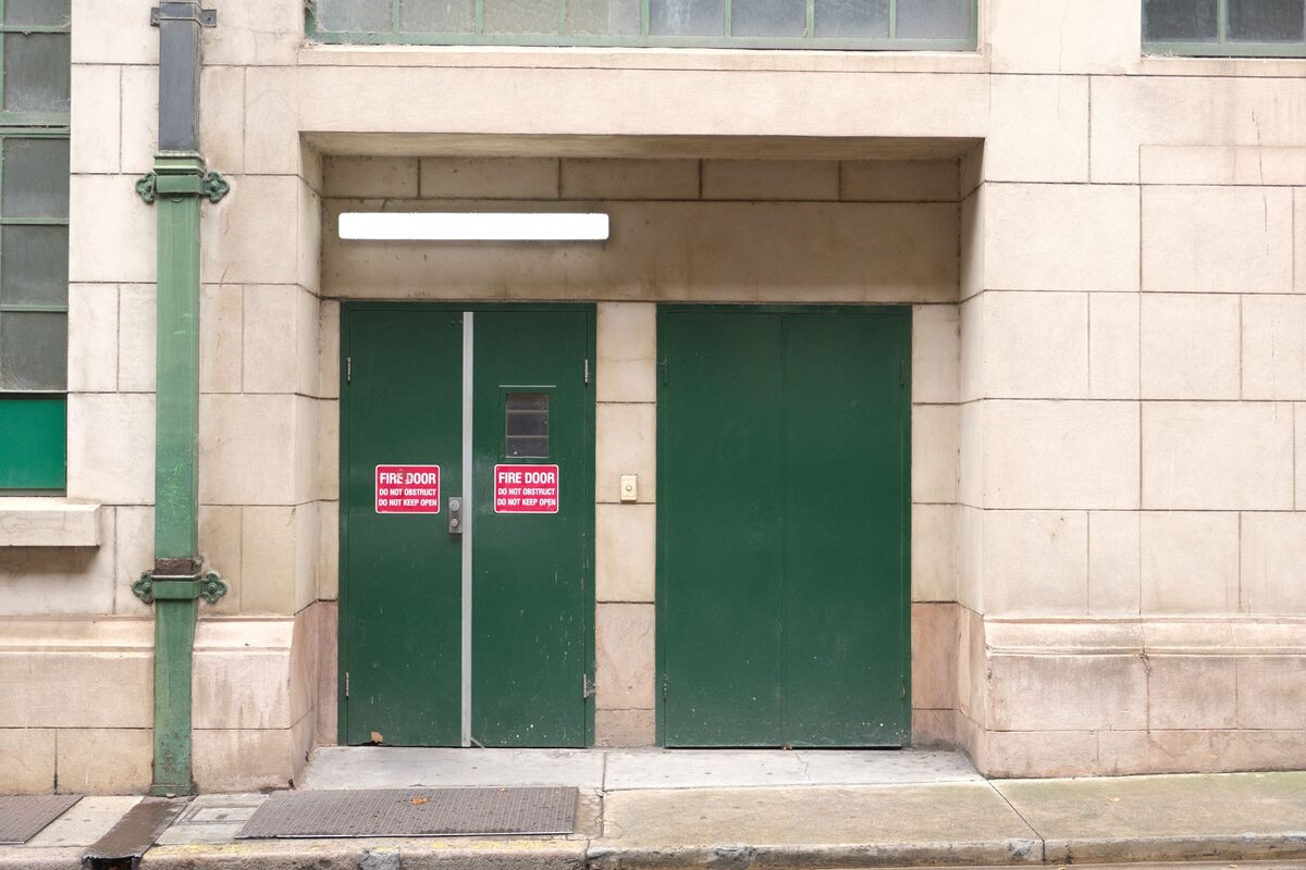Green metal fire doors on a New York City building marked do not obstruct and do not keep open