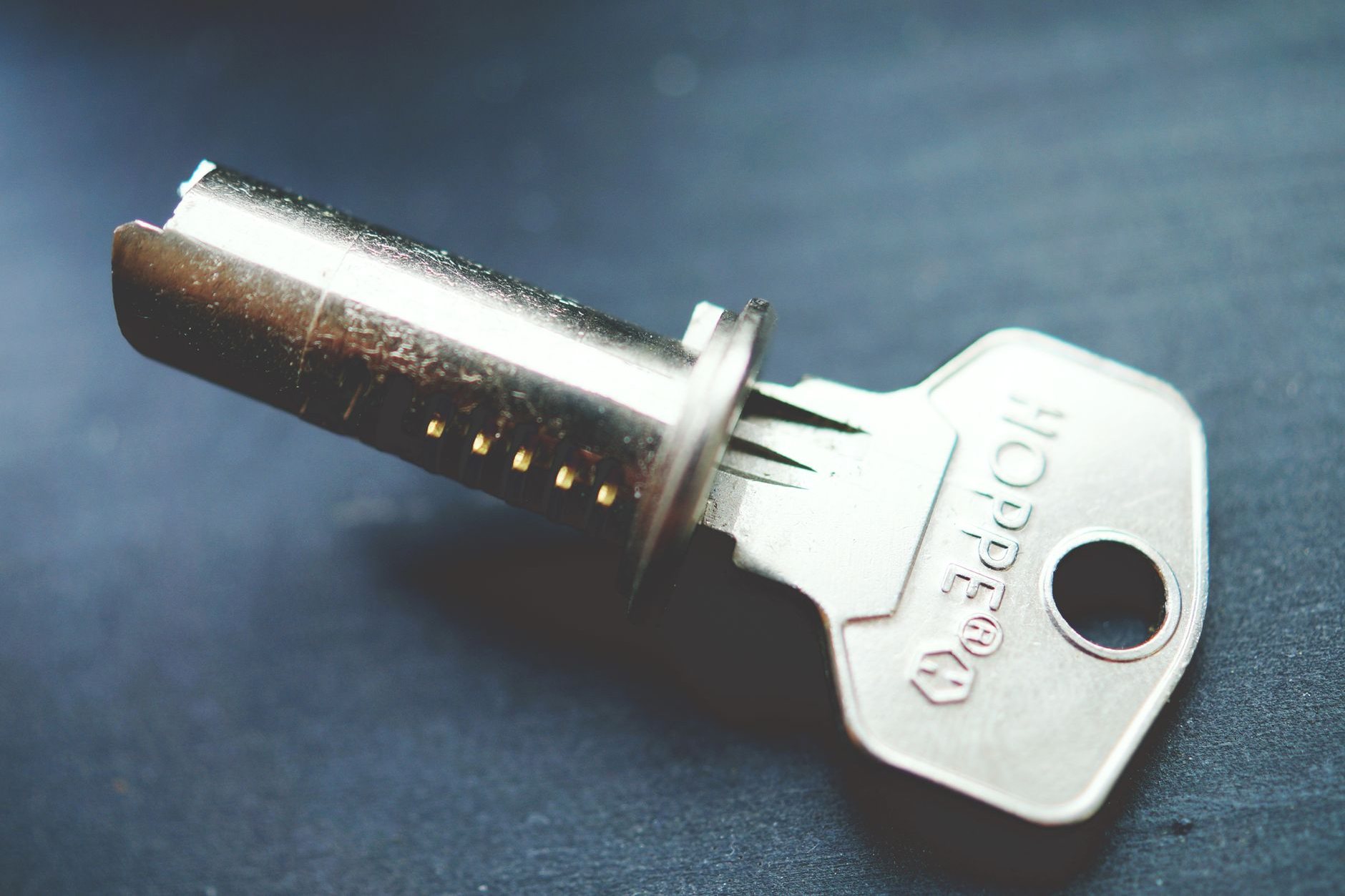 A lock cylinder plug removed from its housing with a key inserted, showing the pin chambers and wear along the keyway