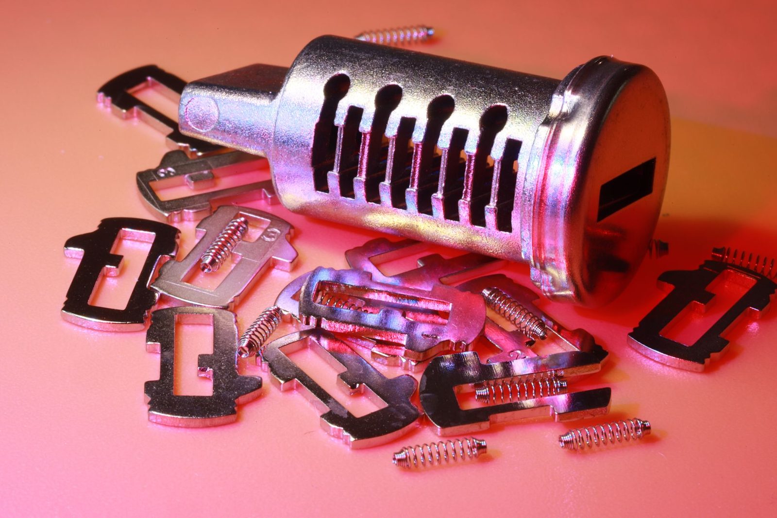 Disassembled lock cylinder beside its loose pins, wafers and springs, the parts a locksmith reconfigures when rekeying a lock