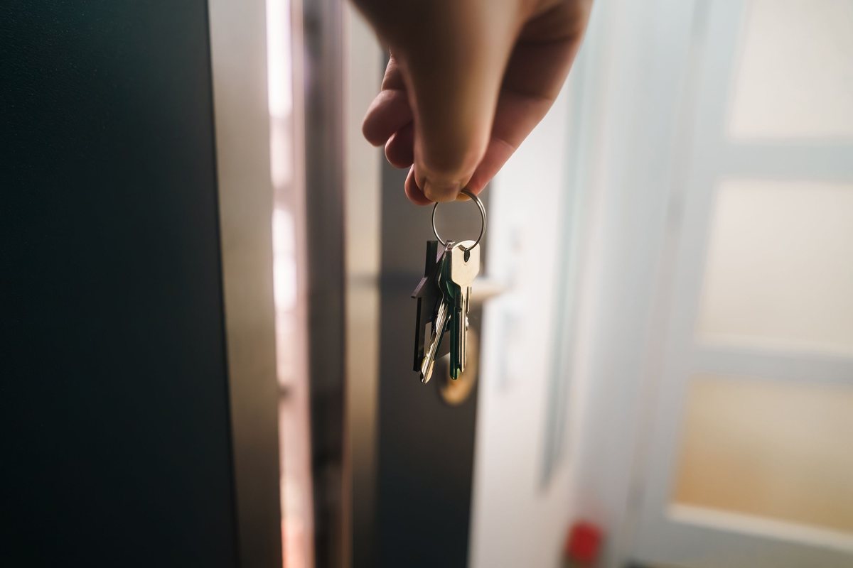 Hand holding a set of apartment keys in an open doorway