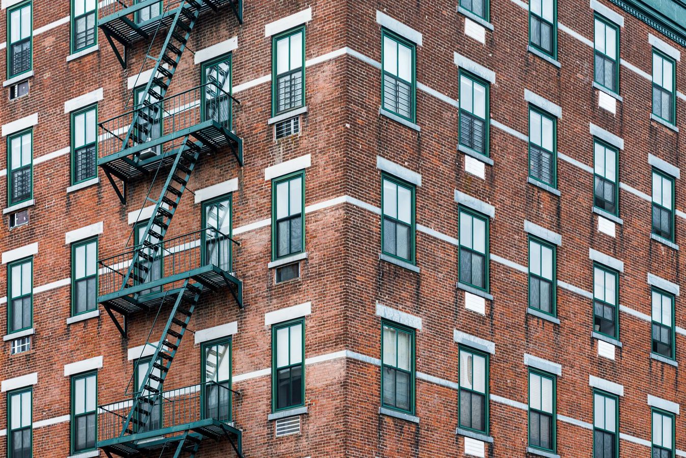 Red brick New York City apartment building with iron fire escapes running past the windows