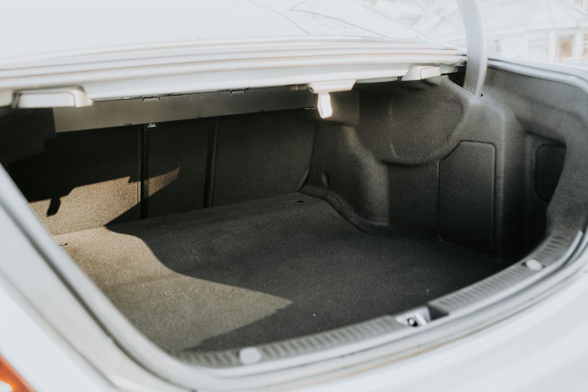 Open and empty car trunk lit by daylight, seen from behind the vehicle
