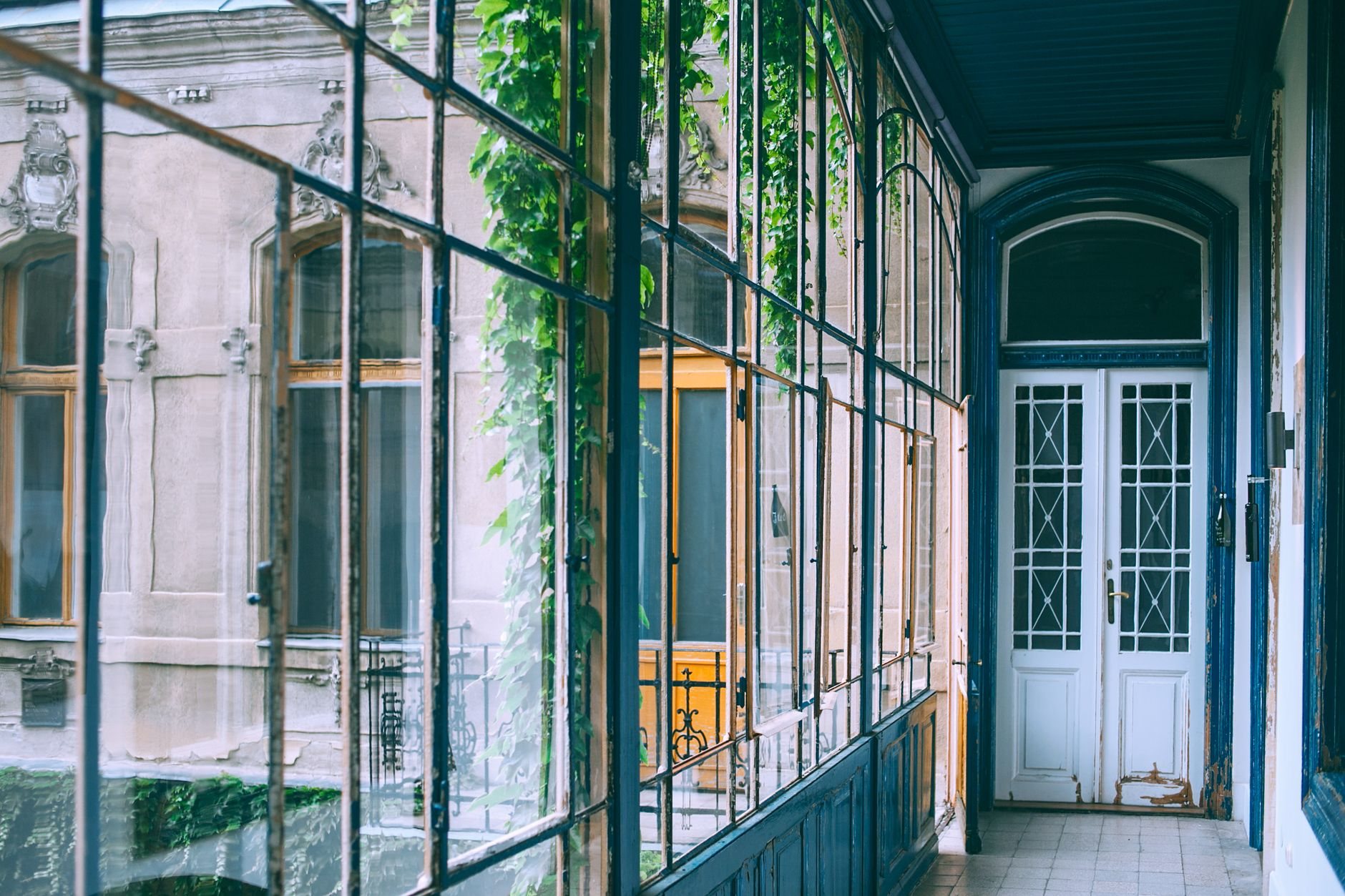 Glazed gallery in an older building with white French doors opening onto an enclosed terrace
