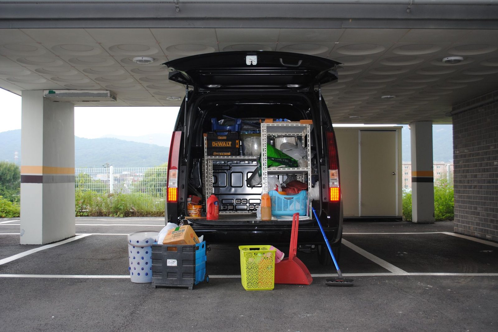 Open rear of a work van showing shelving racks loaded with power tools and equipment